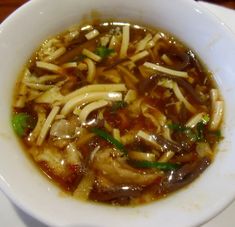 a white bowl filled with noodle soup on top of a table