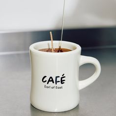 a coffee cup with a spoon sticking out of the inside of it that says cafe