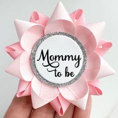 a close up of a person holding a pink flower with the words mommy to be on it