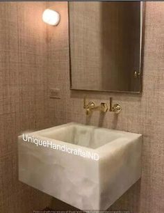 a white sink sitting under a bathroom mirror next to a wall mounted faucet