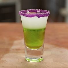 a green and white drink sitting on top of a wooden table