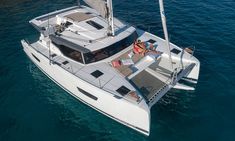 a catamaran sailing in the ocean with people lounging on it's deck