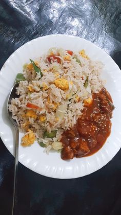 a white plate topped with rice and meat next to a fork on top of a table