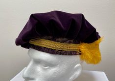 A new adult professional quality Renaissance Medieval Tudor dark purple velvet muffin floppy hat.  This purple and gold brocade band hat is embellished with a stunning gold braid and purple ostrich feather.  Inside lining. New not worn. A great accent for your Medieval Renaissance outfit for your reenactment event, theme party or stage production. All sales final. Will exchange for a different size. Size X small has a 21 1/2" band Size small has a 22" band Size medium has a 22 1/2" band Size large has a 23" band Size X large has a 23 1/2" band Size XX large has a 24" band Adjustable Purple Hat For Costume, Purple Mardi Gras Costume Accessories, Stage Production, Gold Brocade, Ostrich Feather, Costume Cosplay, Ostrich Feathers, Purple Velvet, Hat Band