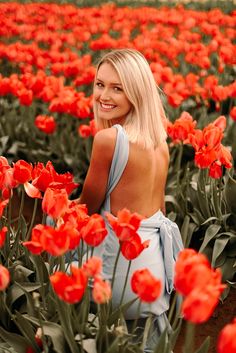 a woman standing in a field of red tulips with her back to the camera