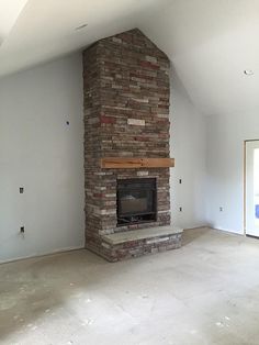 an empty room with a brick fireplace in the middle