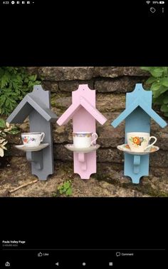 three colorful bird houses with cups and saucers on them