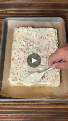 someone is spreading icing on a cake in a pan with a spoon and knife