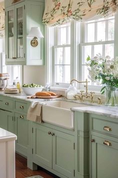 a kitchen filled with lots of green cabinets and white counter tops next to a window