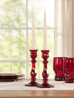 red candlesticks sit on a table with plates and glasses