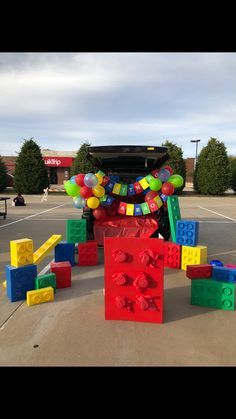 a bunch of legos that are in the street near a building with balloons attached to it