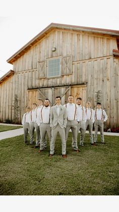 a group of men standing next to each other in front of a barn