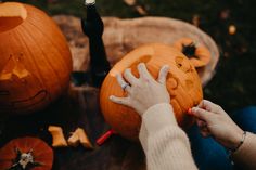 a person carving pumpkins with their hands and other halloween decorations around them on the ground