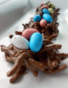 a white plate topped with chocolate and candy covered birds nests on top of marshmallows