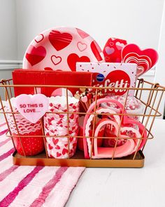 a basket filled with valentine's day items on top of a pink and white table cloth