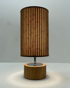 a lamp that is on top of a wooden base and has a bamboo shade over it