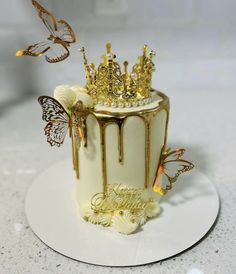 a white cake with gold decorations and butterflies on top