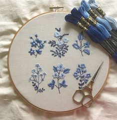 the embroidery is being worked on with blue thread and scissors, along with other items