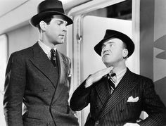 two men in suits and hats standing next to each other