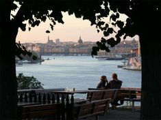 two people are sitting on benches overlooking the water