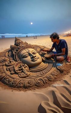 a man sitting on top of a sandy beach next to a sand sculpture