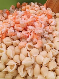 pasta with shrimp and carrots in a green bowl next to a wooden spatula