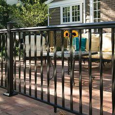 an iron fence with sunflowers on it in front of a house and patio