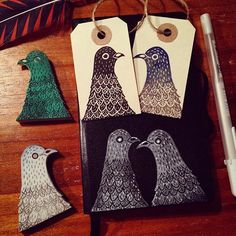 three birds are sitting next to each other on a table with two tags hanging from it's sides