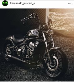 a black motorcycle parked in front of a building with the sun shining down on it