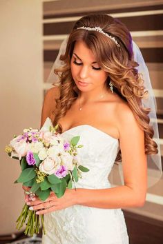 a woman in a wedding dress holding a bouquet and looking down at her phone screen