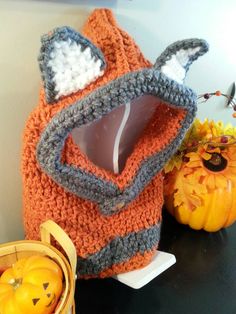 an orange and gray knitted bag sitting on top of a table next to pumpkins