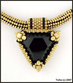 a black and gold necklace is shown with beads on the bottom, and an open triangle shaped