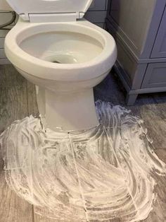 a white toilet sitting on top of a wooden floor