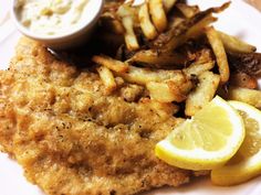 fried fish with fries and lemon wedges on a plate