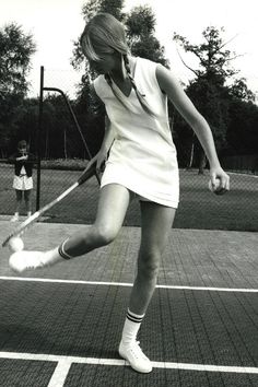 a woman swinging a tennis racquet on top of a tennis court