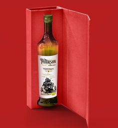 a bottle of whisky in a red box on a red surface with the lid open