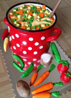 a cake made to look like a pot full of soup with carrots and peas