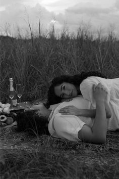 a woman laying on the ground in front of some bottles and wine glasses with her arms around her body