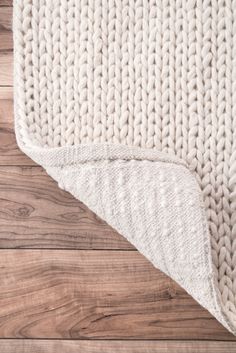 a white rug on top of a wooden floor next to a wood flooring board