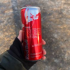 a person holding a red energy drink in their hand