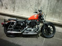 an orange motorcycle parked next to a concrete wall