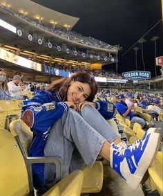 a woman sitting in the bleachers at a baseball game wearing blue and white sneakers