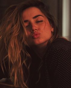 black and white photo of a woman with long hair blowing out her nose while sitting down