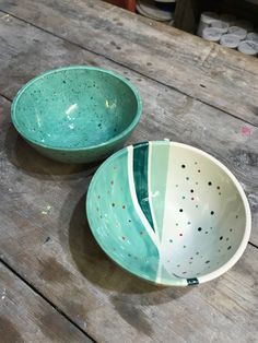 two bowls sitting on top of a wooden table next to each other with holes in them