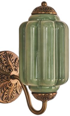 a green glass wall light with an ornate design on the back of it's arm