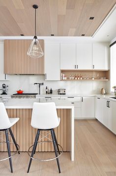 two stools are in the middle of a kitchen with white cabinets and wood flooring