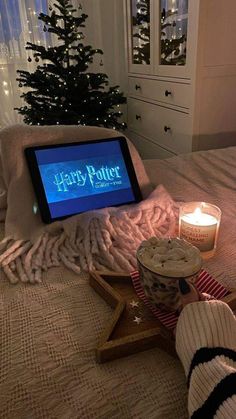 a harry potter tablet sitting on top of a bed next to a cup and candle