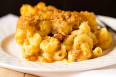 macaroni and cheese casserole on a white plate with a black fork