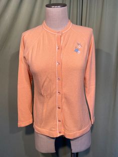 an orange cardigan sweater on a mannequin's dummy with grey background