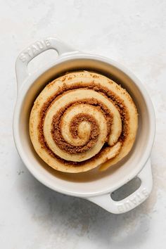 two cinnamon rolls in a white bowl on a table